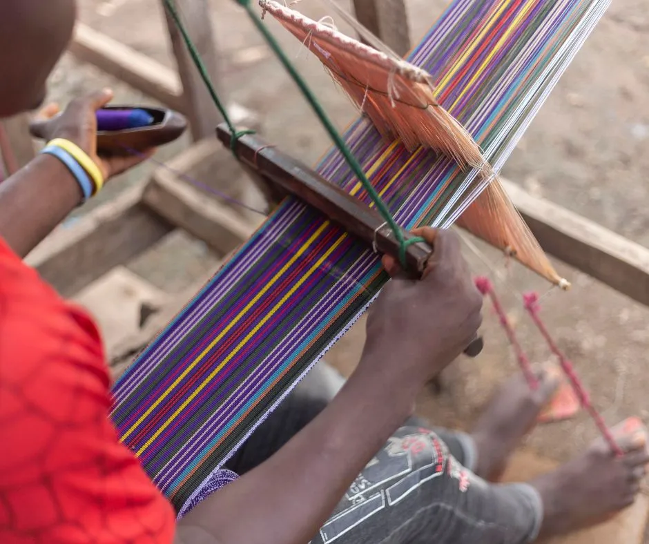 Image of a male aso oke weaver using a horizontal double heddle loom. (Circa 2020)