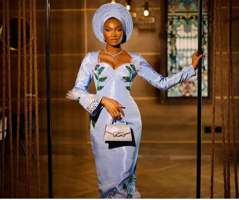 Wofaifada in her serulean blue aso oke personalized with beading and tulle detailing on the sleeves and hem
