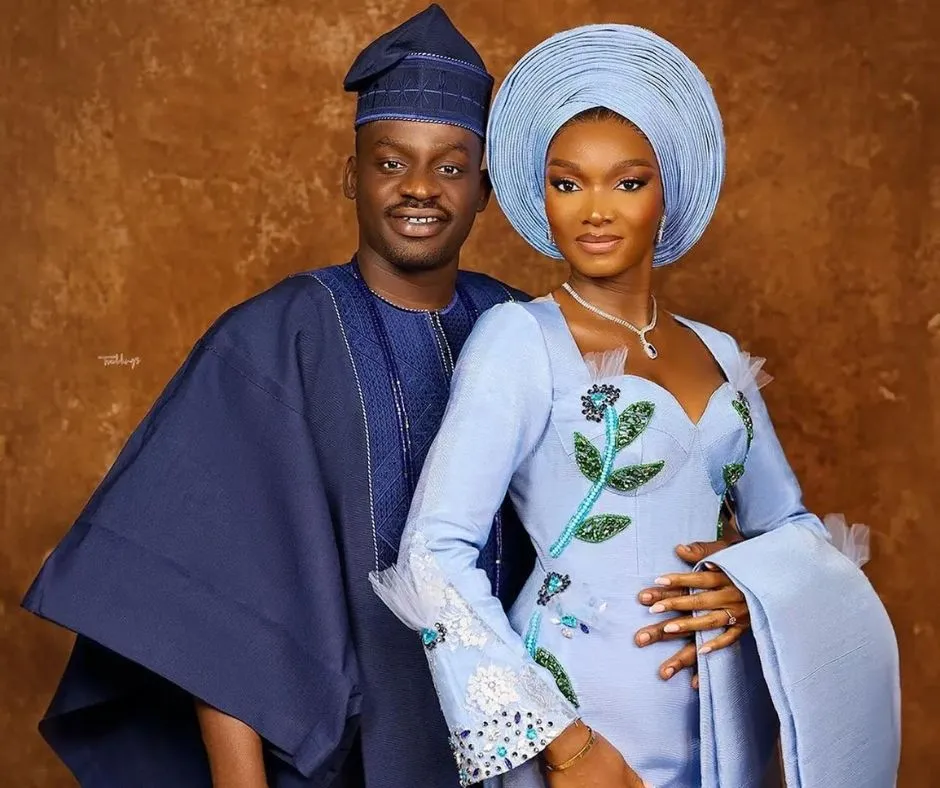 Wofaifada and taiwo cole in their wedding aso oke, with wofai in a cerulean blue dress with flowery embellishments and tulle, and taiwo in a nacy blue aso oke agbada
