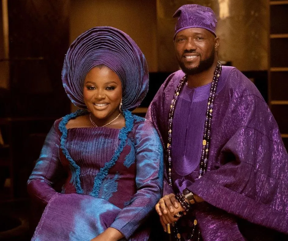 Sunmisola and Yinka Okeleye in their wedding aso oke with sunmisola wearing a duotone outfit in purple and blue shades with burgundy accents. WHile her husband is in a purple metallic aso oke agbada